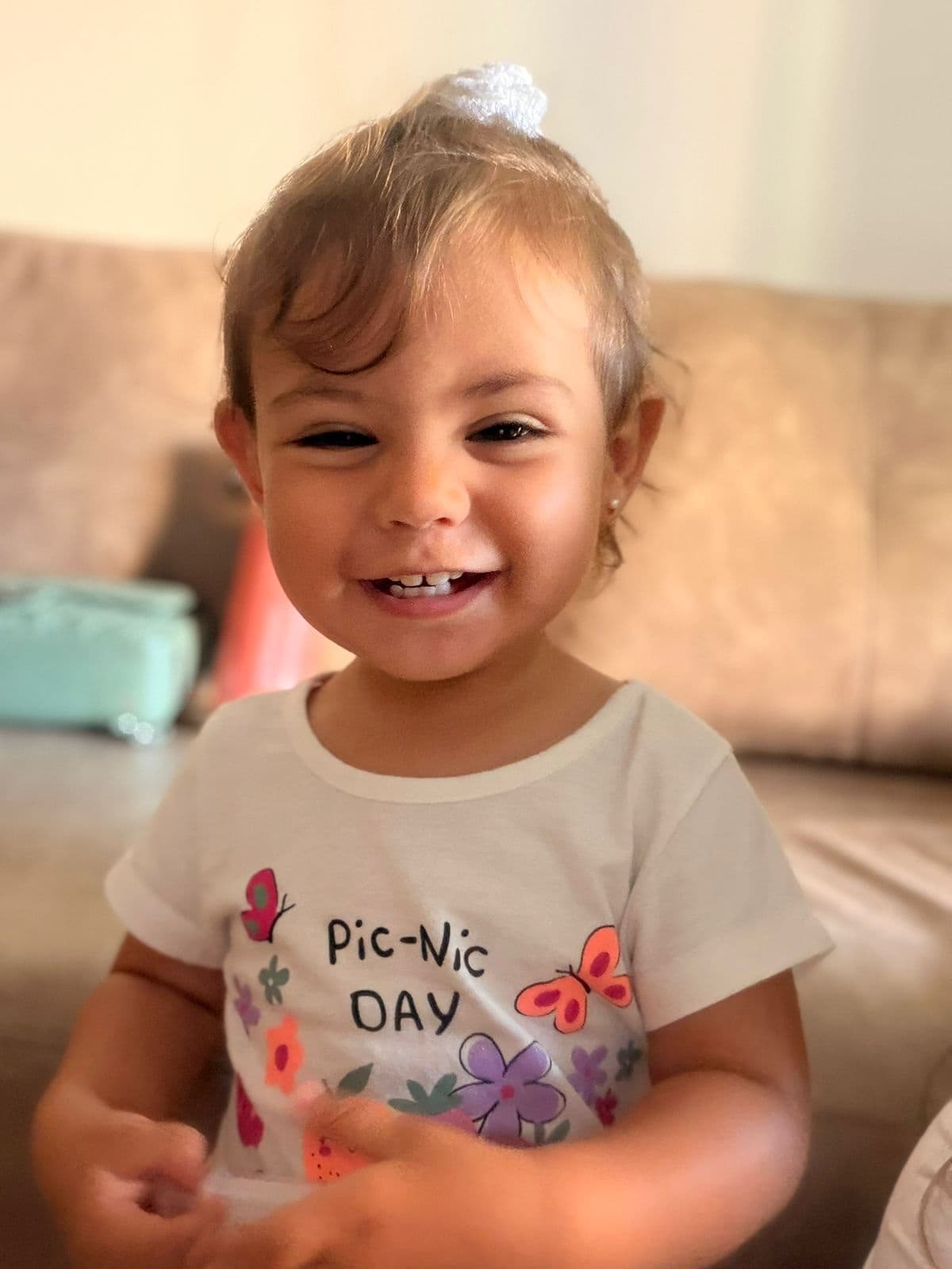 Lara sorrindo com um lacinho branco no cabelo